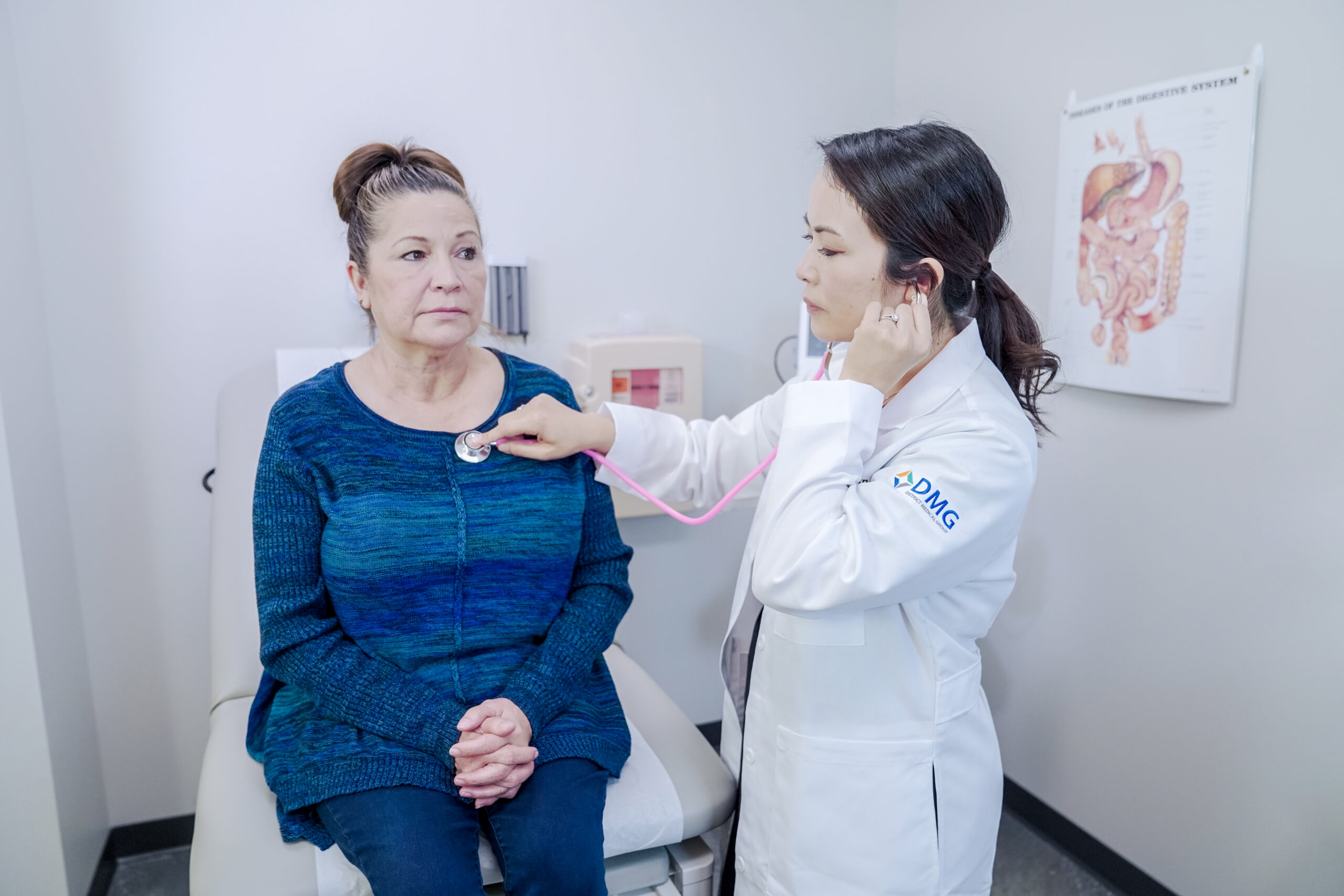 A female doctor using a stethoscope to check a hispanic women