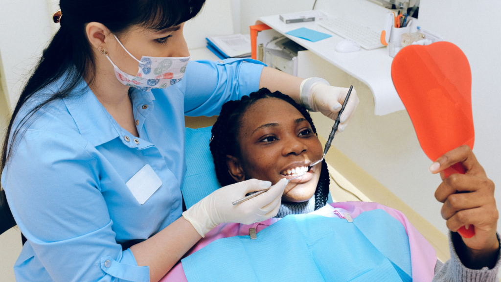 a teenager sits in a dental chair while a dentist examines their teeth