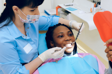 a teenager sits in a dental chair while a dentist examines their teeth