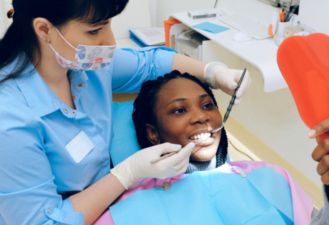 a teenager sits in a dental chair while a dentist examines their teeth
