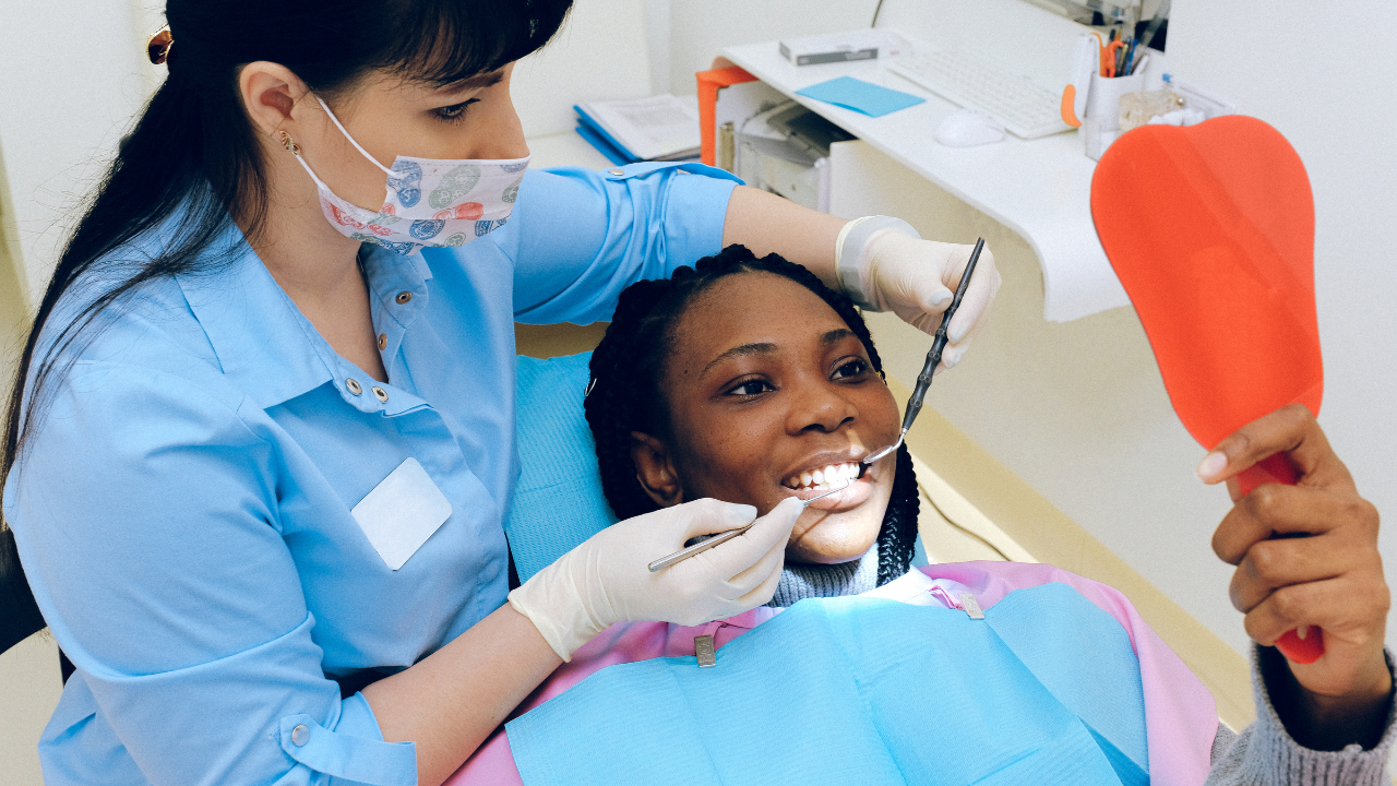 a teenager sits in a dental chair while a dentist examines their teeth
