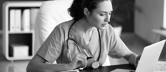 medical professional with a stethoscope researching on a laptop - black and white